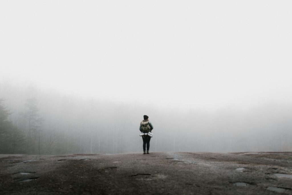 Person standing on the edge of a foggy trail