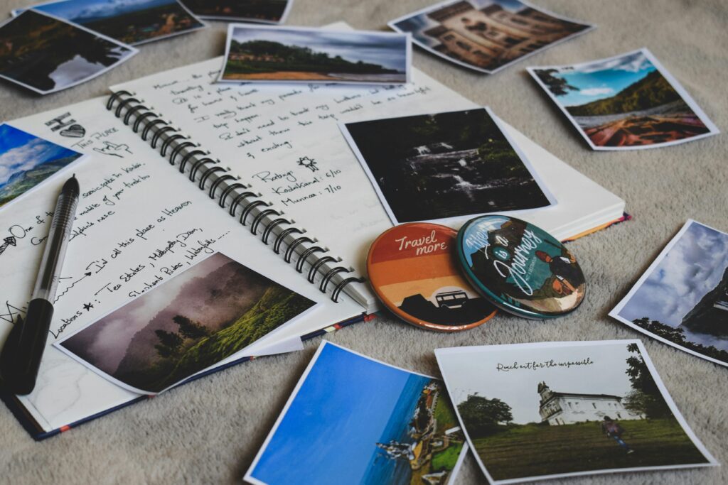 A flatlay of a journal open and polaroid photos of travel adventures scattered on top
